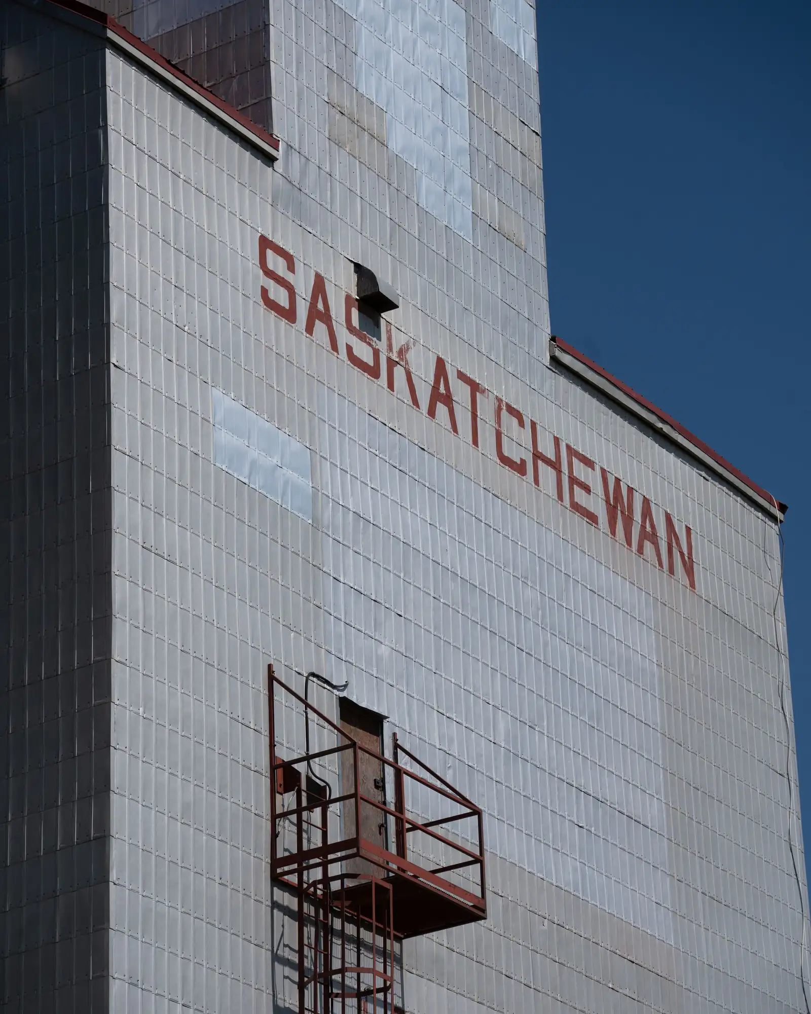 A weathered grain elevator painted with the word Saskatchewan against a blue sky