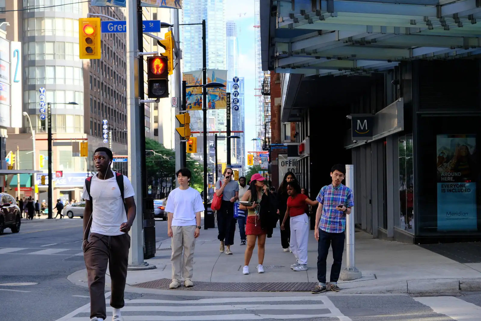 People crossing a busy downtown intersection on a sunny day